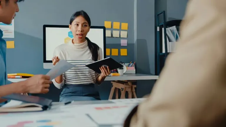 Team meeting as a woman presents ideas using a tablet in a modern office.