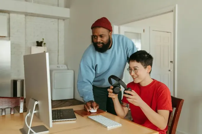 Two people collaborating on a computer at a desk.