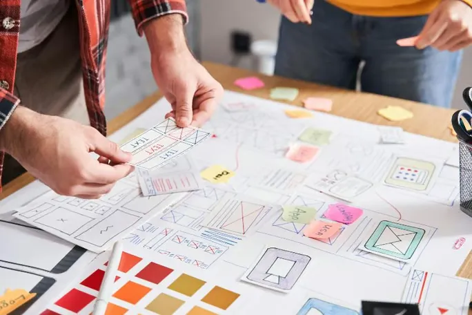 Team planning a content distribution layout with wireframes and notes on a desk.