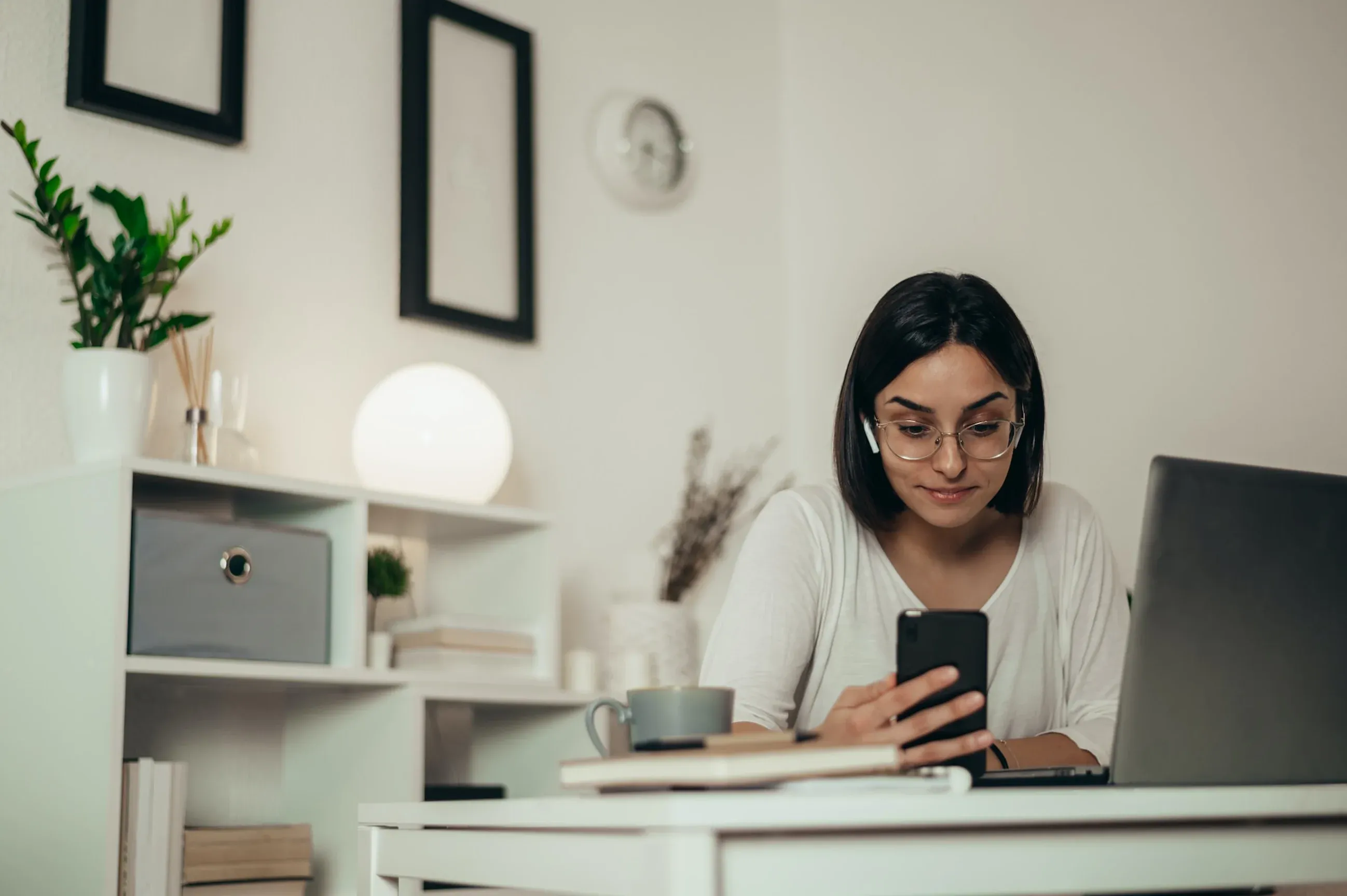 Woman using an AI detector while working at a desk with a phone and laptop.