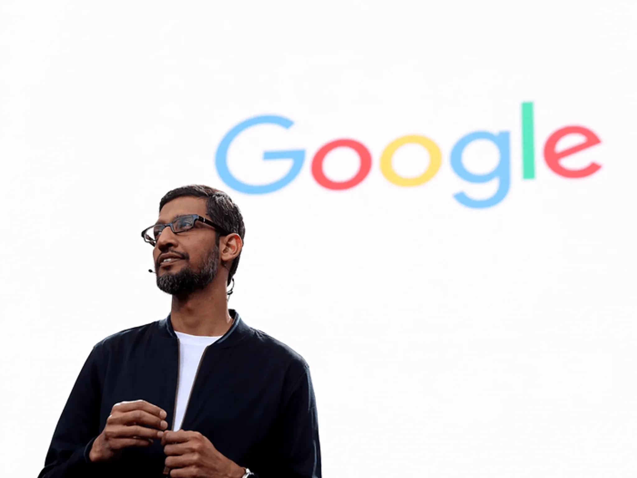 Speaker presenting in front of a large Google logo backdrop.